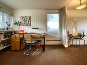 A small study with a small book shelf towards the left corner and a back door to the center.