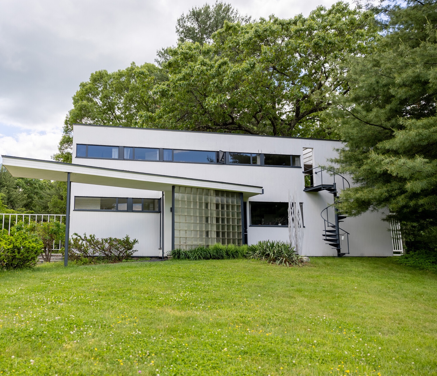 A photo of the exterior of Groupius House. The lawn is green and the leaves of the trees are green.
